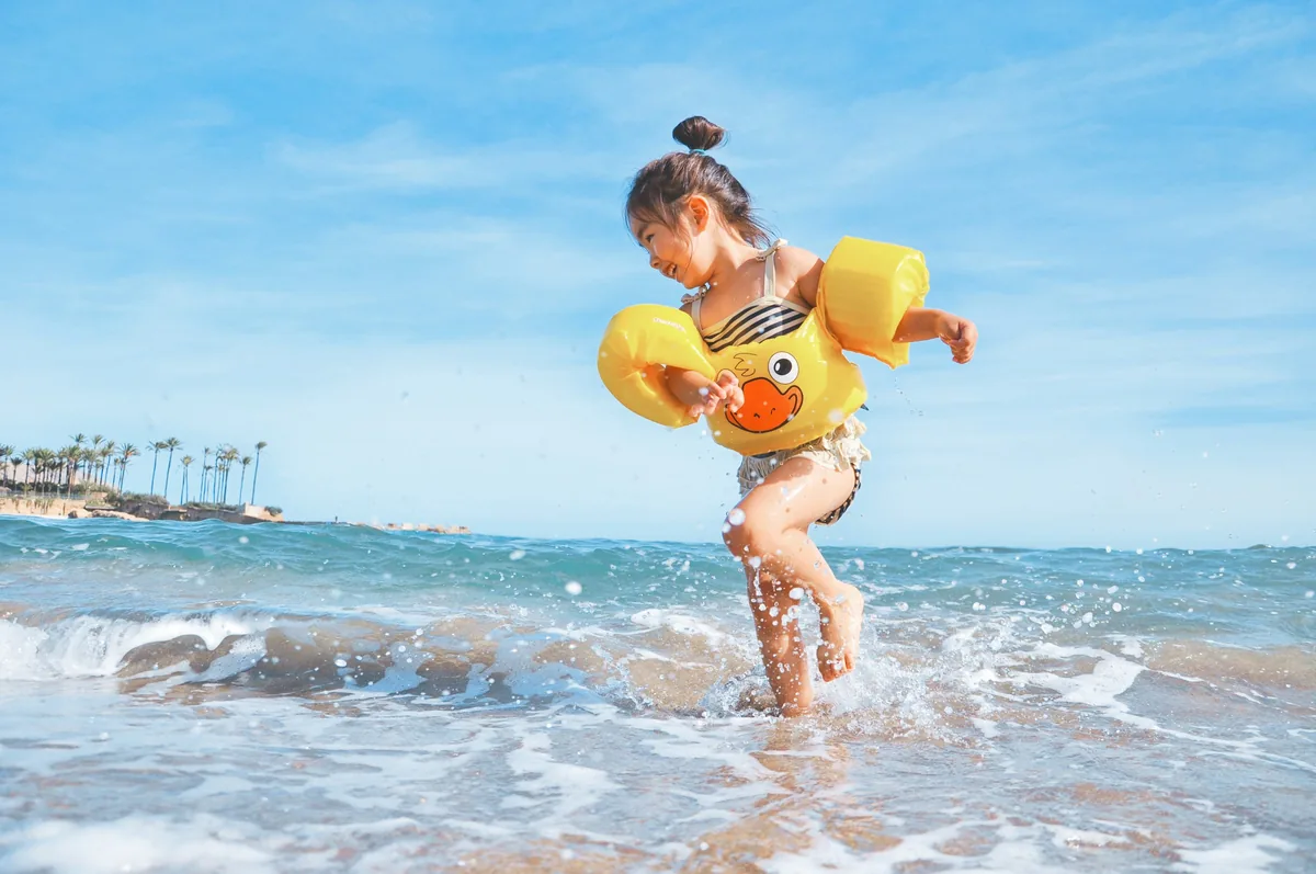 浮き輪をつけて波打ち際で遊ぶ女の子