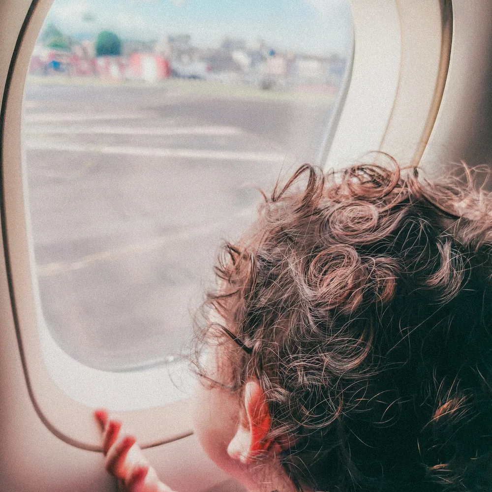 飛行機の窓から外を見る子ども